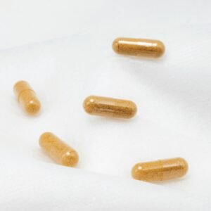 Close-up of brown capsules on a white surface, emphasizing health and supplements.